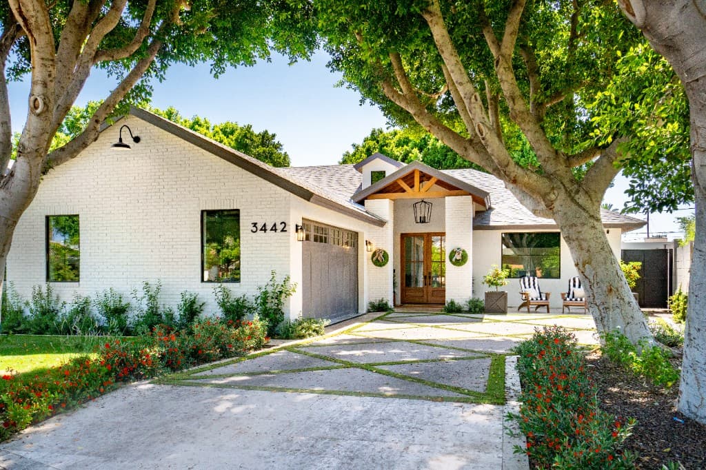 Modern single-story white brick home with landscaped driveway